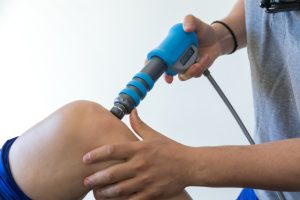 A qualified therapist doing ESWT Shockwave Therapy on a patient.